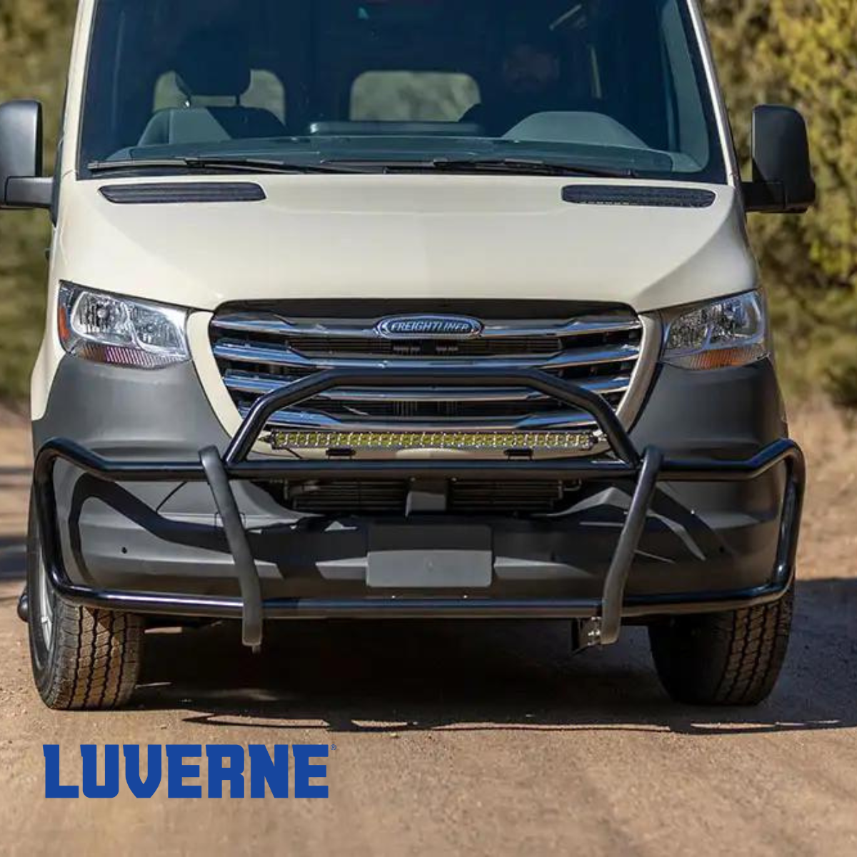 A white van is parked on the side of a dirt road.