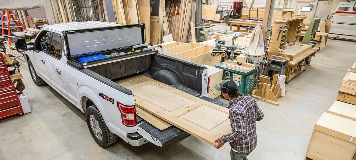 A man is loading wood into the bed of a truck.