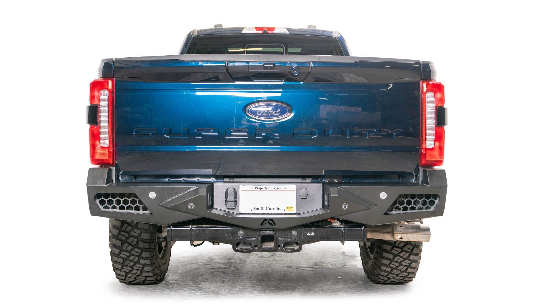 The back end of a blue ford truck with a black bumper.