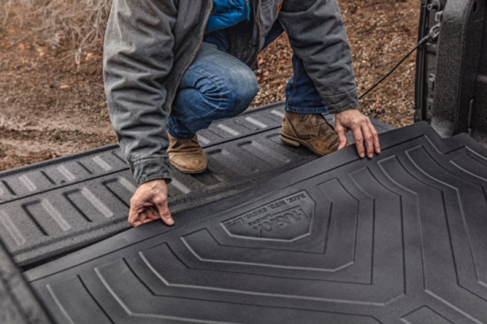 A man is kneeling down in the back of a truck.