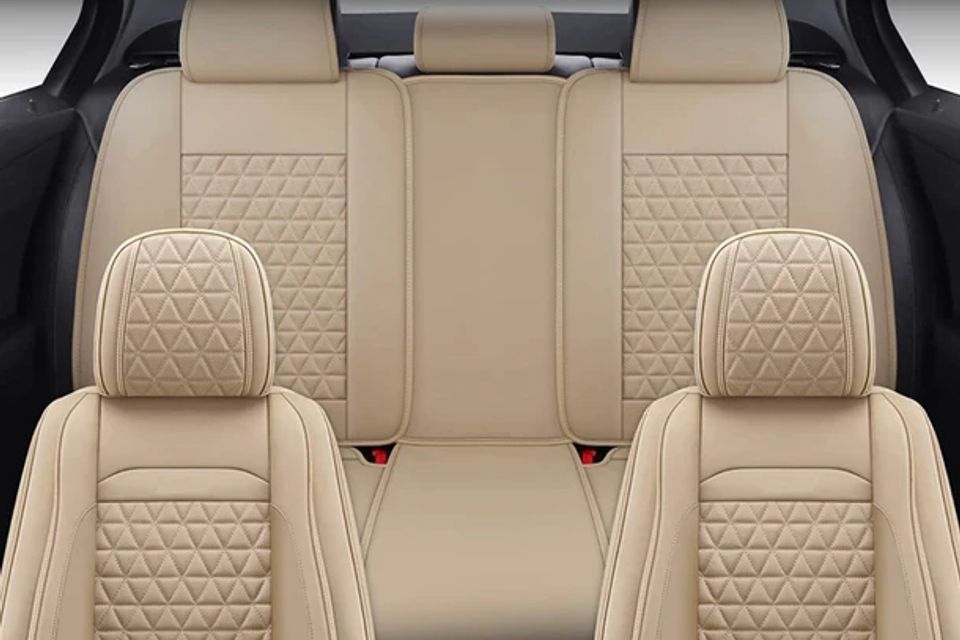 The back seat of a car with beige seat covers and headrests.