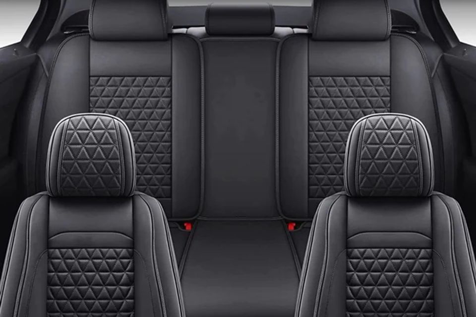 The back seat of a car with black leather seat covers.