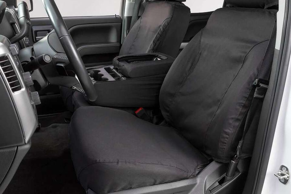 A white truck with black seat covers and a steering wheel.