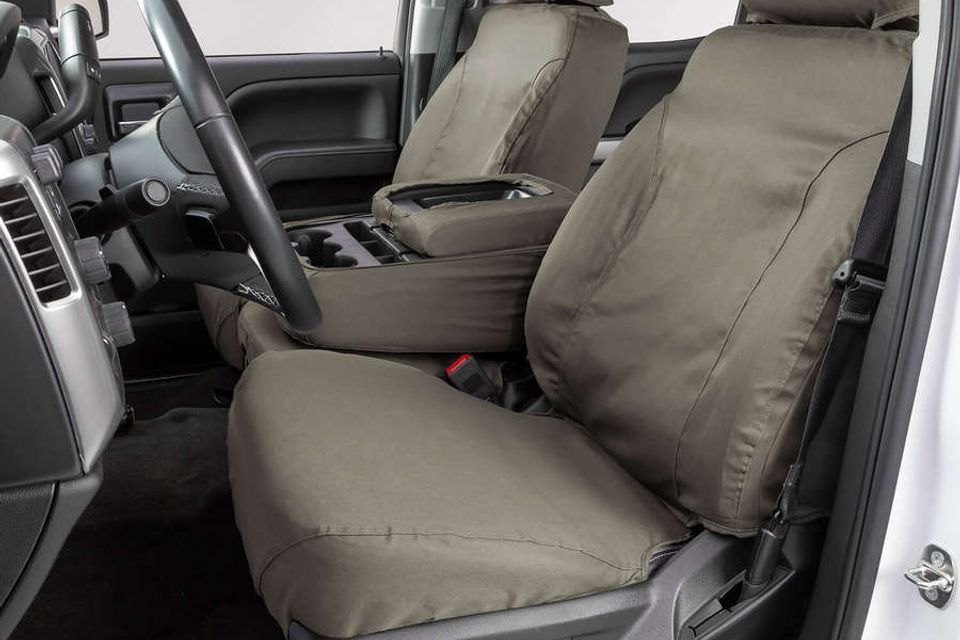 The front seats of a white truck with seat covers on them.