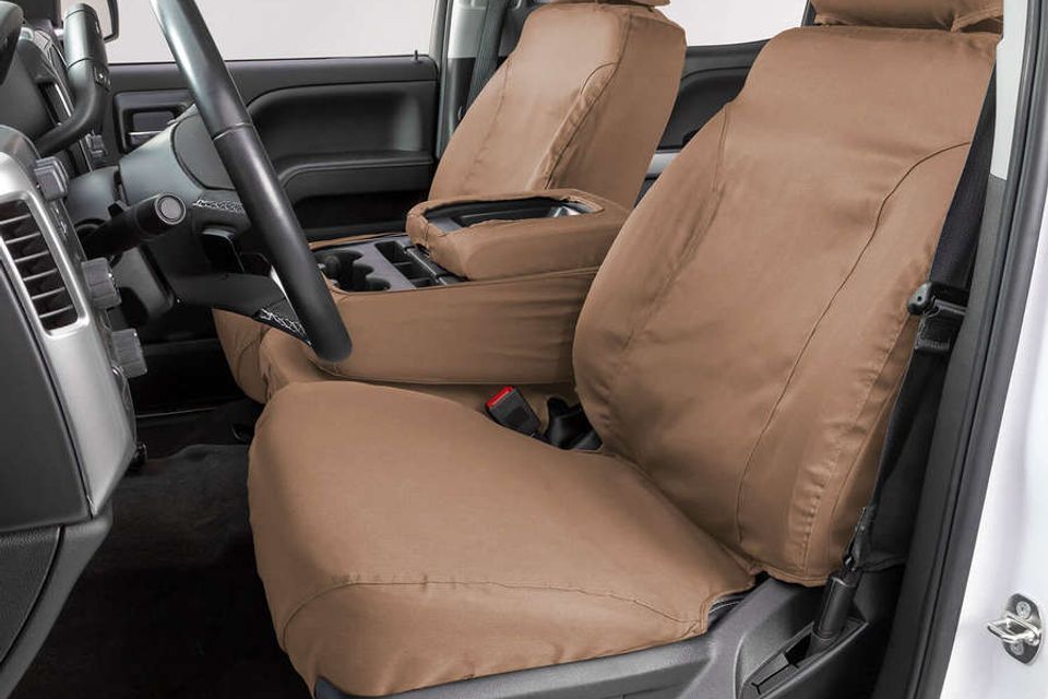 A white truck with brown seat covers and a steering wheel.