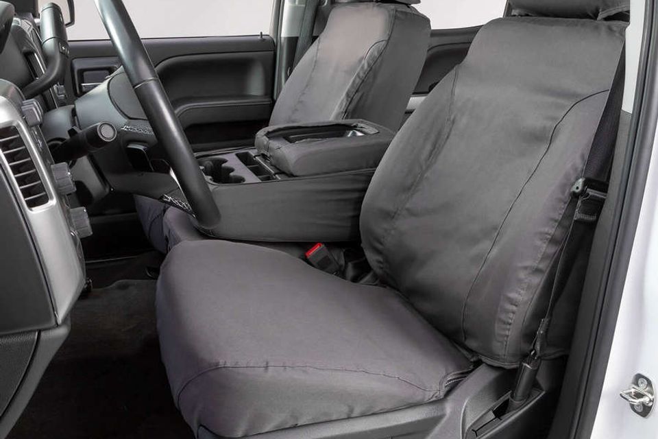 A white truck with black seat covers and a steering wheel.