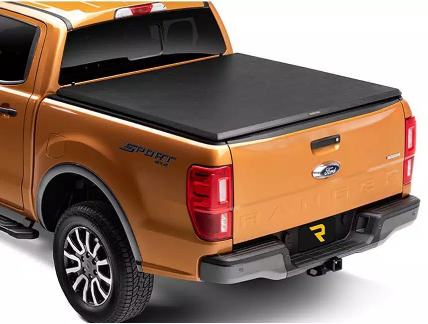 A ford ranger with a black tonneau cover on the bed.