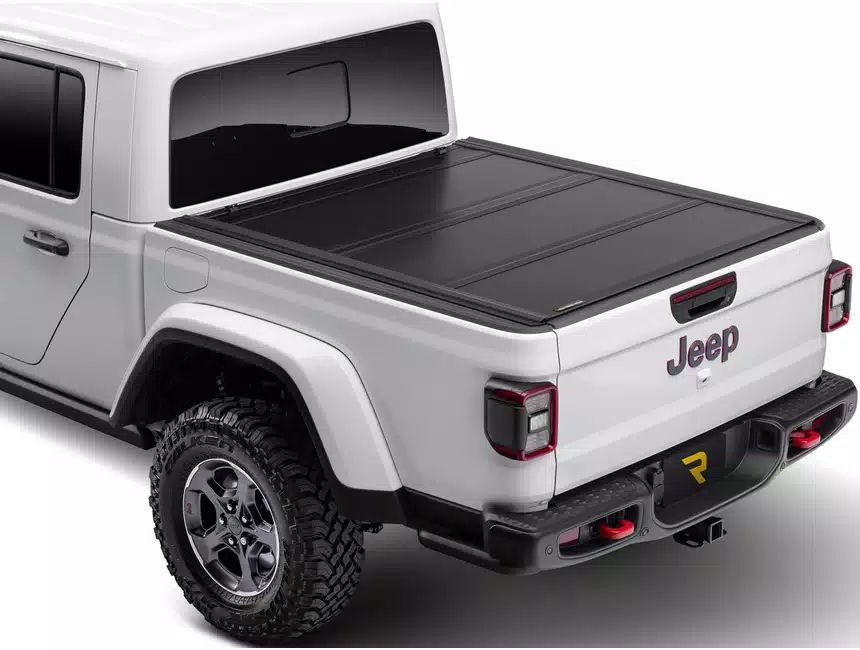 A white jeep with a black bed cover on it.