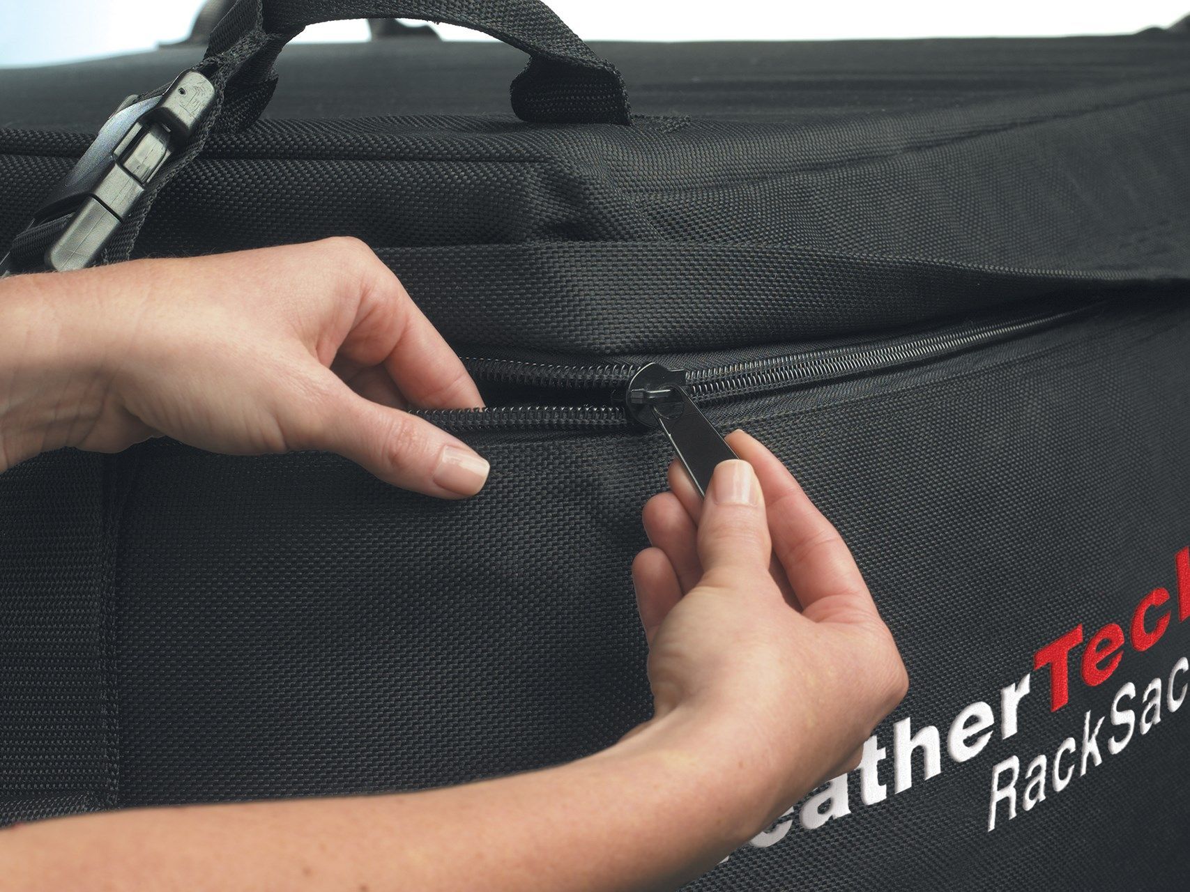 A person is opening a zipper on a black leather tech bag