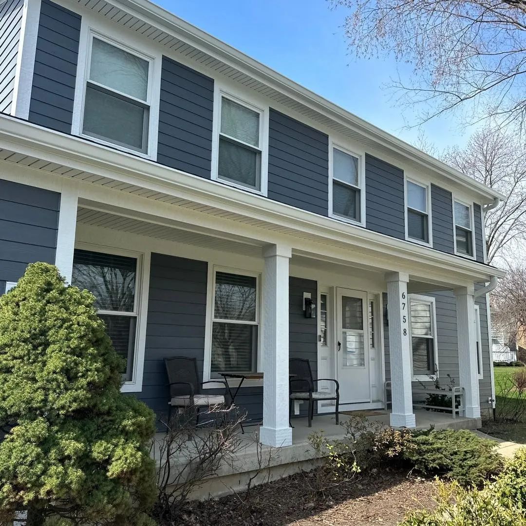 Two-story house with blue siding, white trim, and a covered porch with white columns.