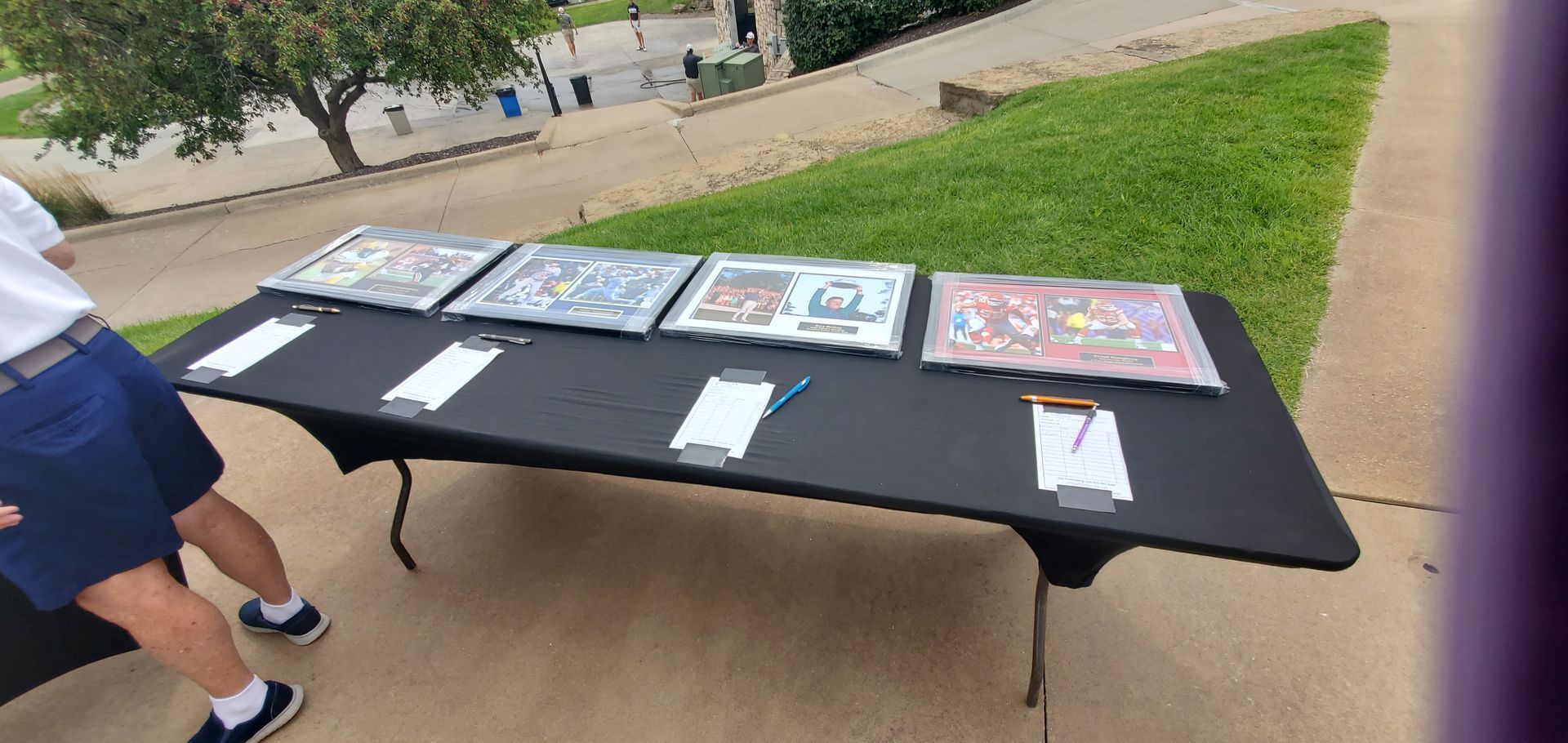 A person sets up a table with framed art outdoors.