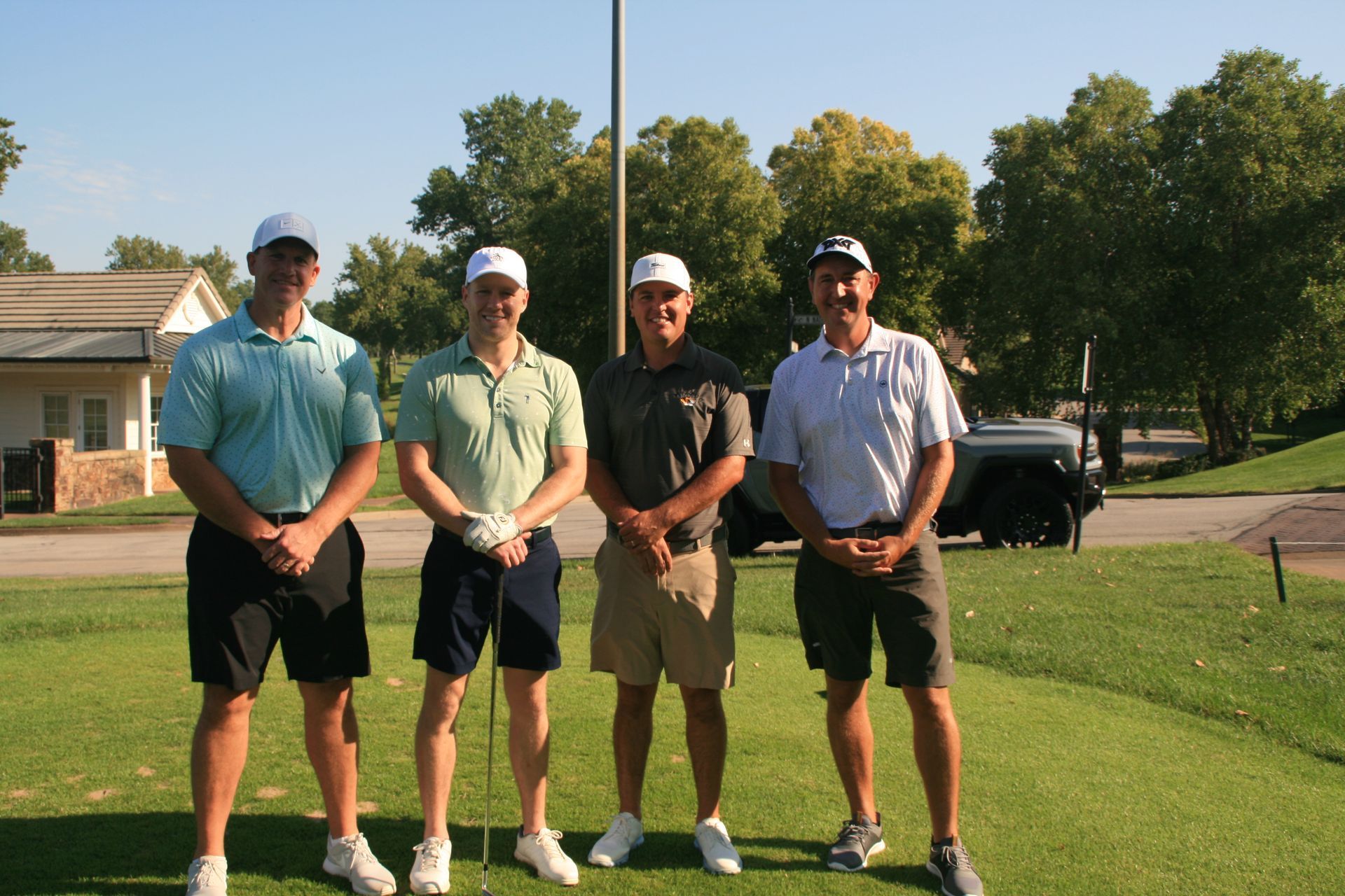 Four men in golf attire standing on a golf course.