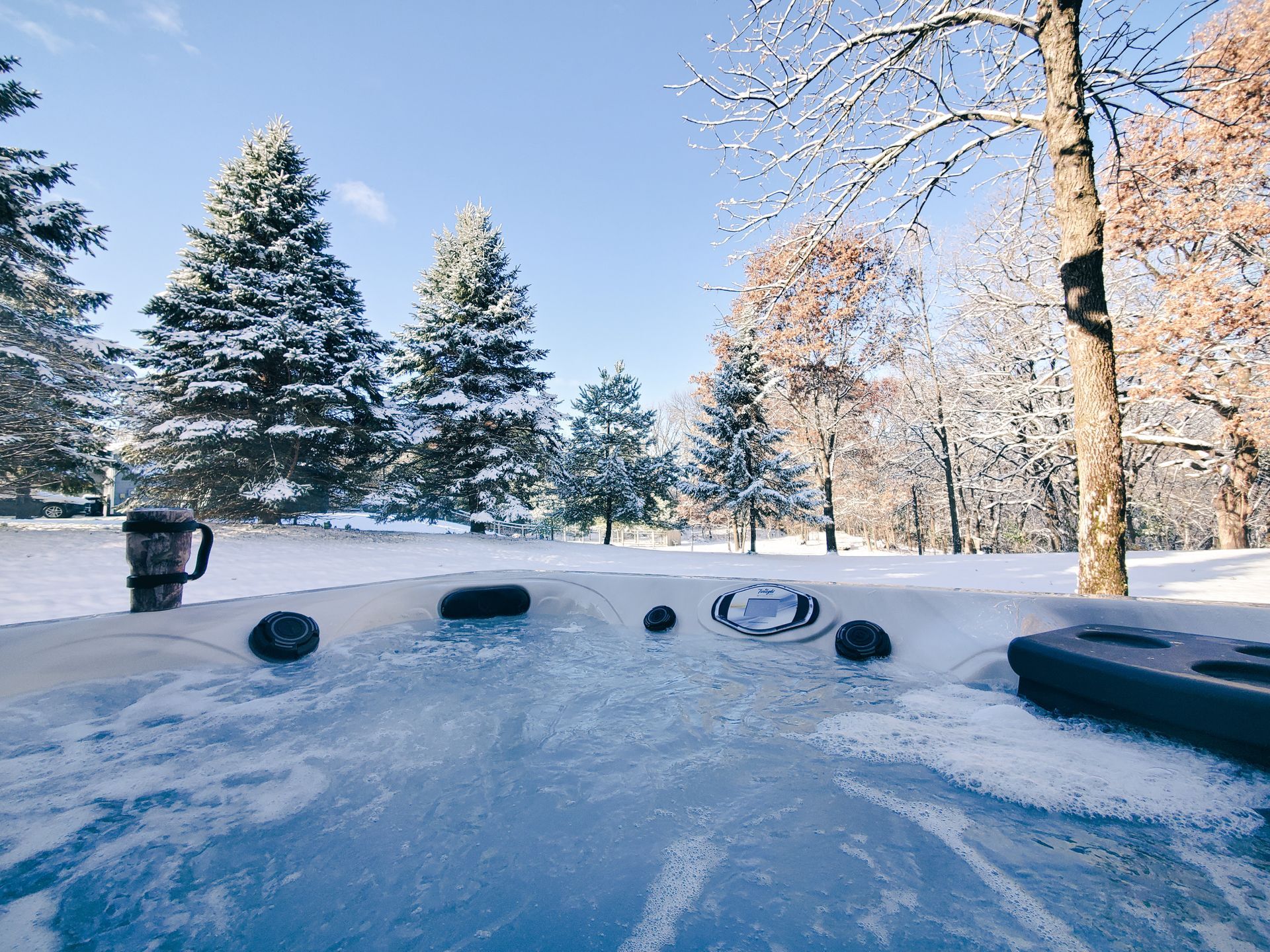 Hot tub steaming in snowy Colorado winter landscape with snow-covered trees.