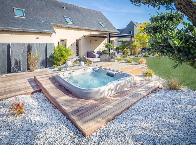 A hot tub is sitting on a wooden deck in front of a house.