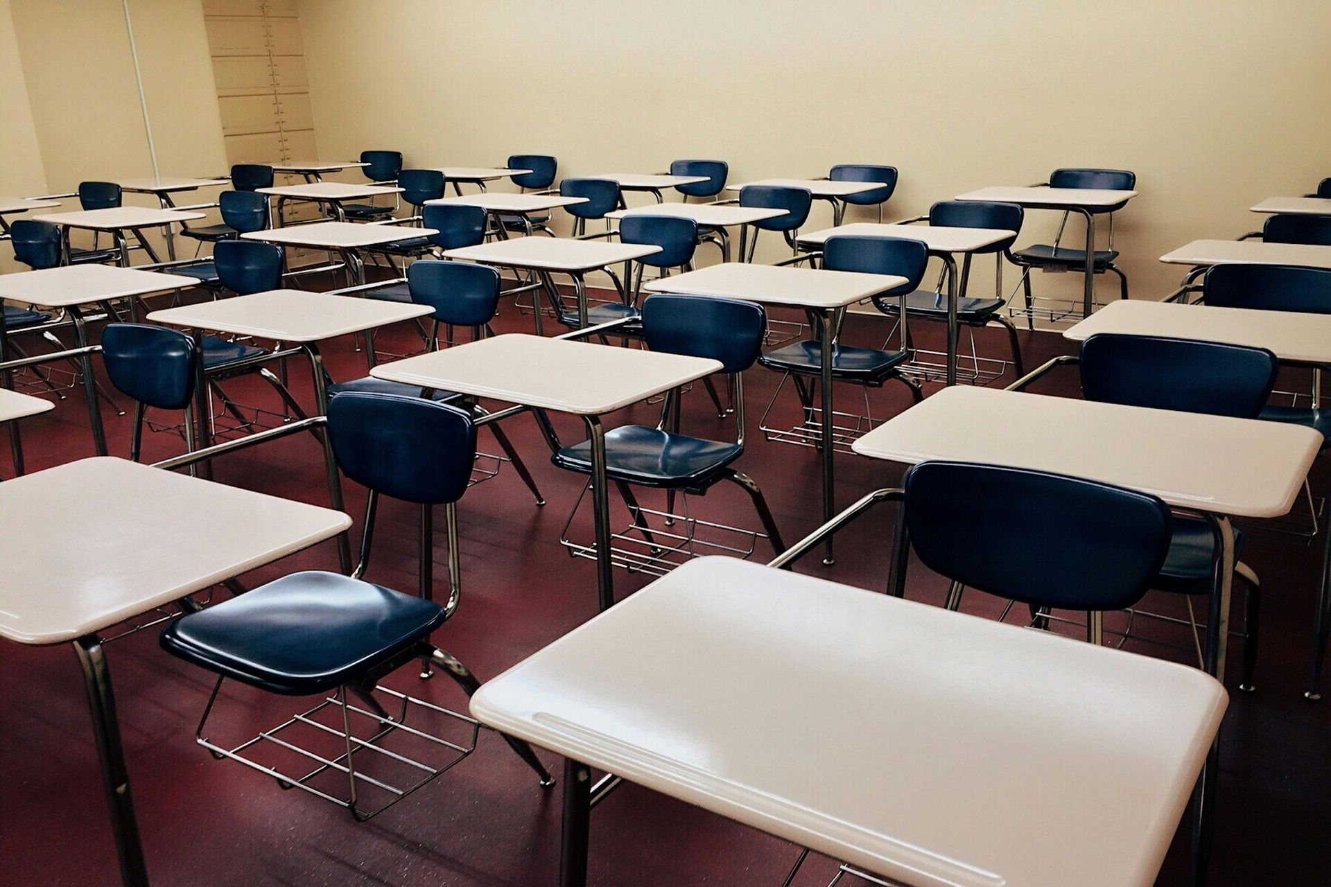 Empty classroom with rows of student desks and chairs.