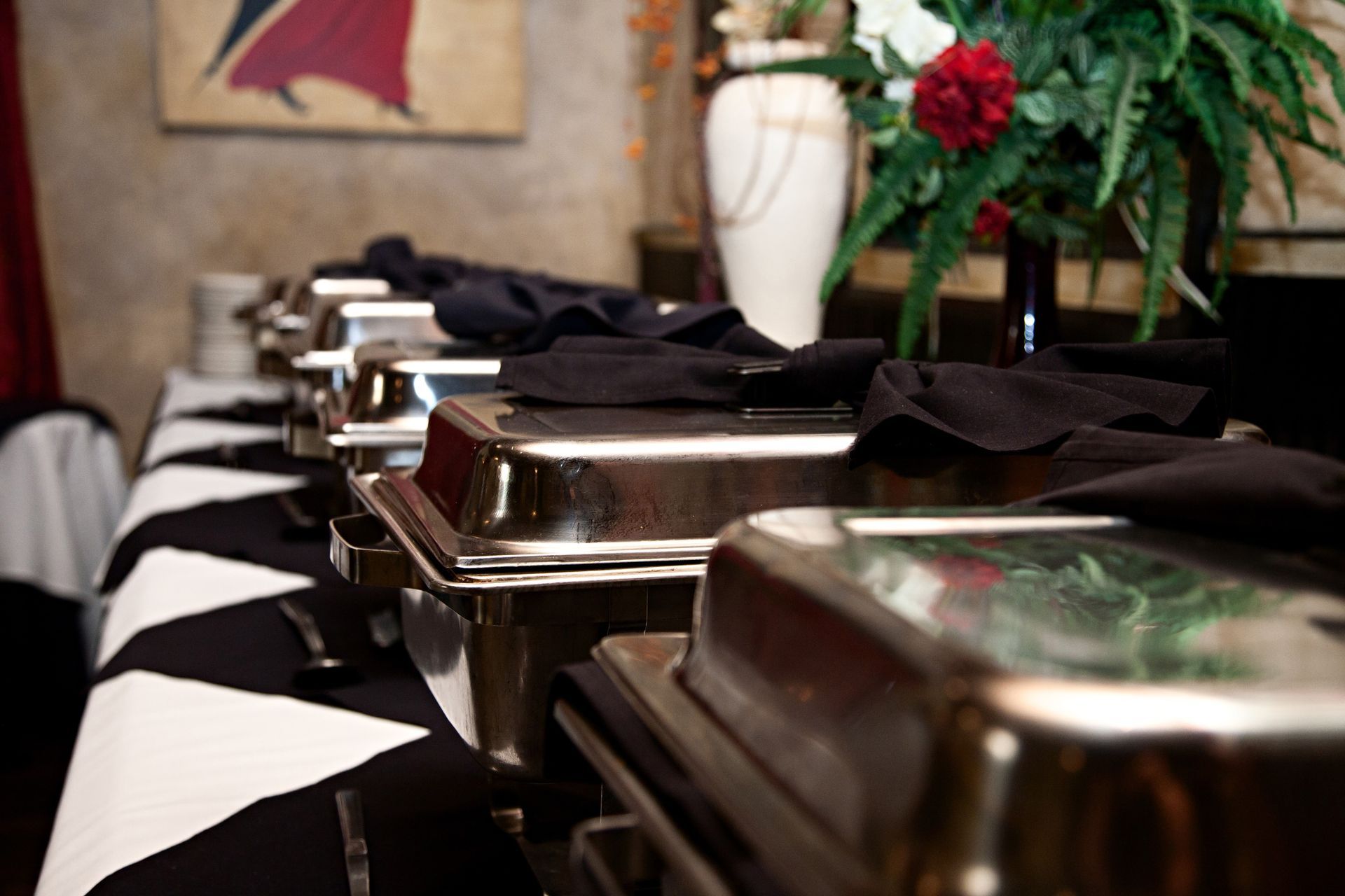 Buffet table with silver chafing dishes and black napkins in a banquet setting