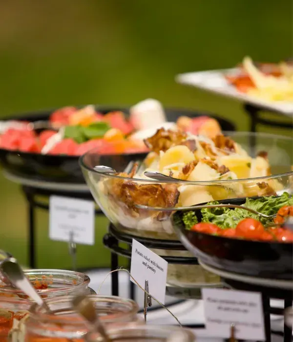 Salads and appetizers in glass bowls on a buffet table with serving spoons