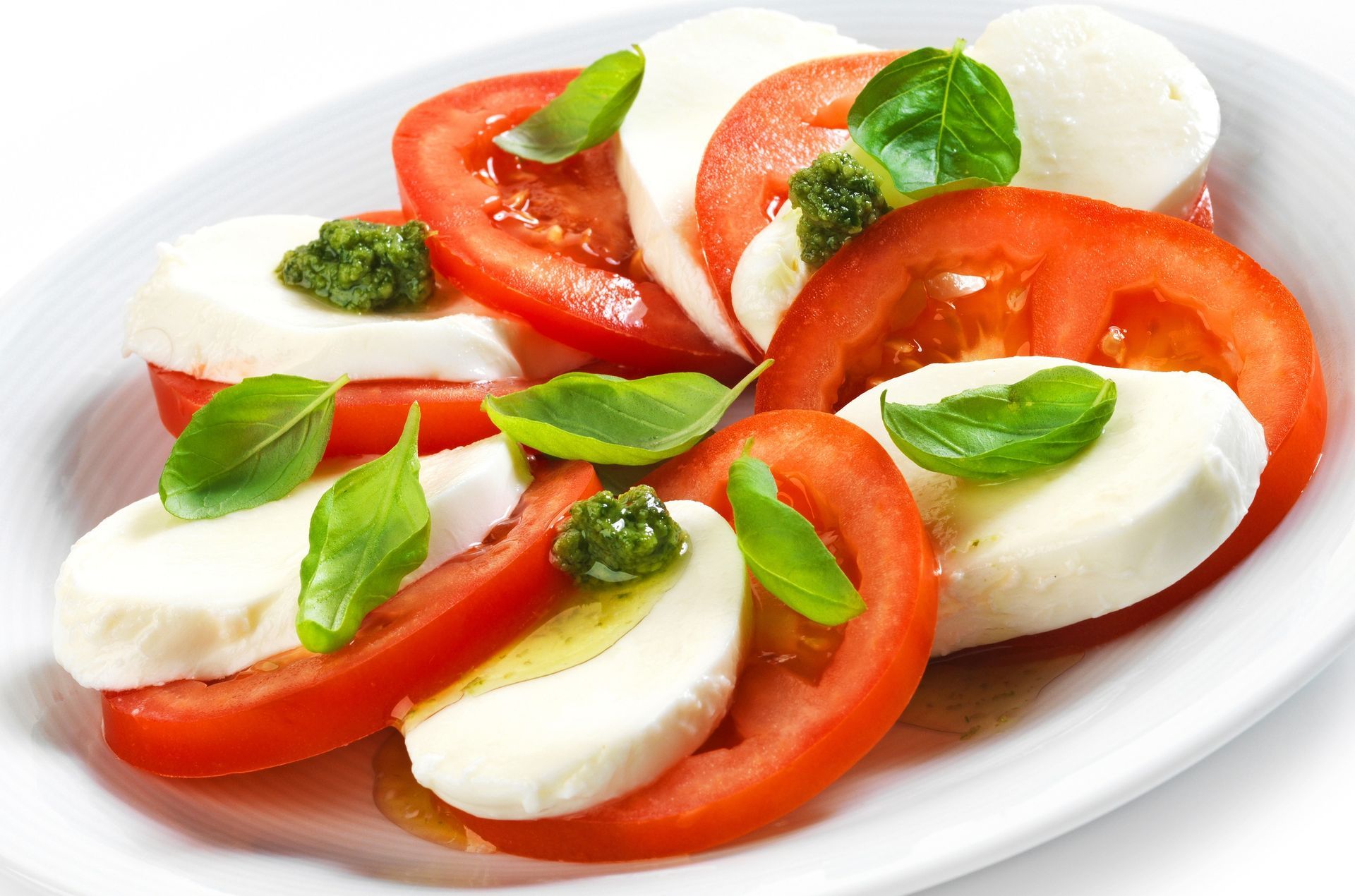 Caprese salad with tomato slices, mozzarella, and basil on a white plate
