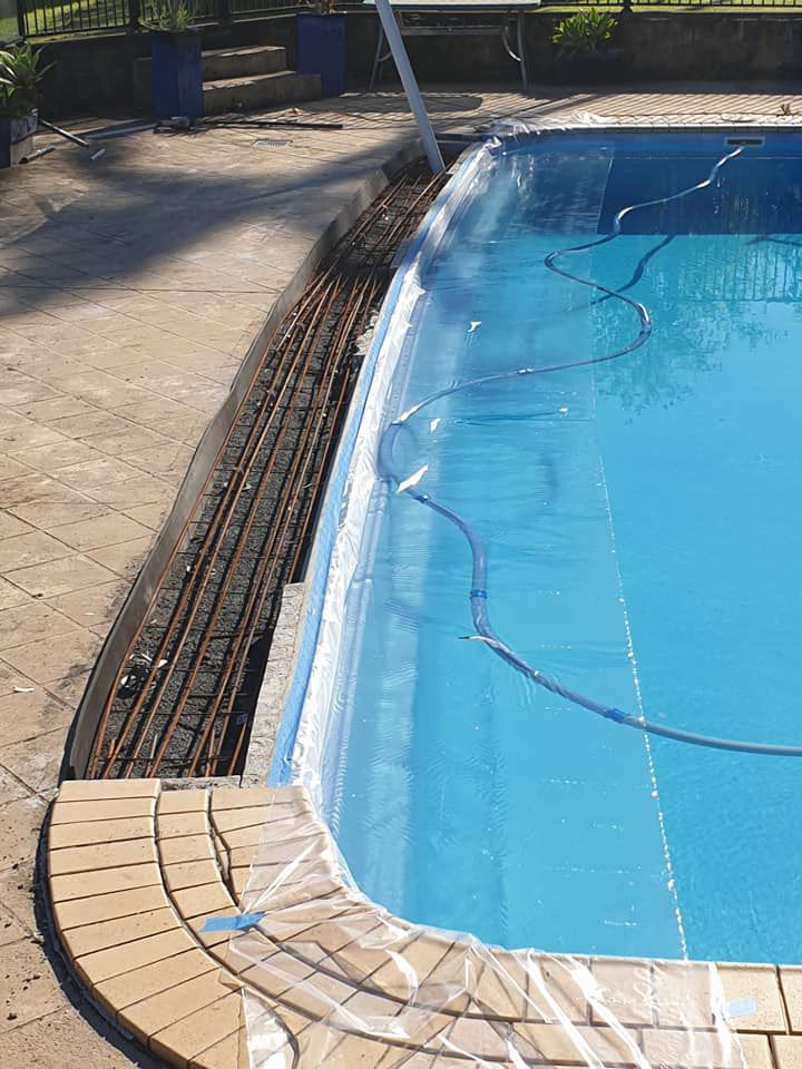 A Swimming Pool Is Being Covered In Plastic And A Train Track Is In The Background — McCarthys Property Services in Woolgoolga, NSW