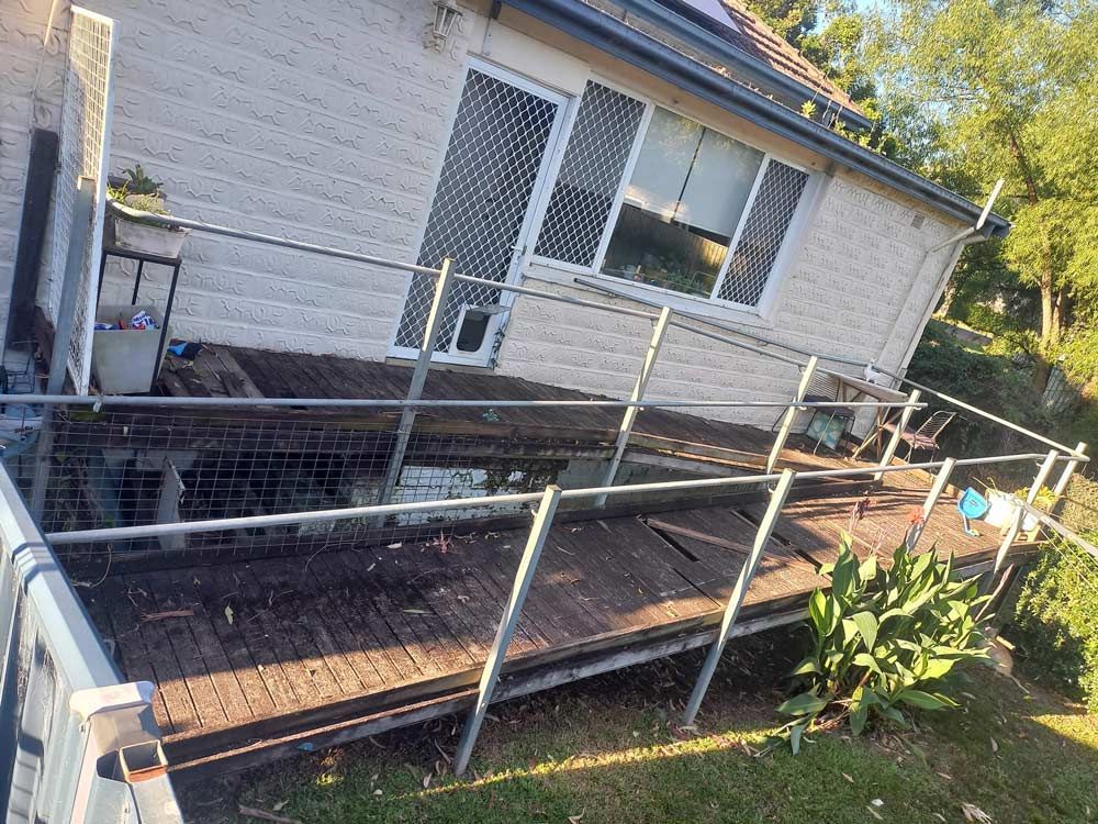 A House With A Wooden Deck And A Fence Around It Before Construction — McCarthys Property Services in Grafton, NSW