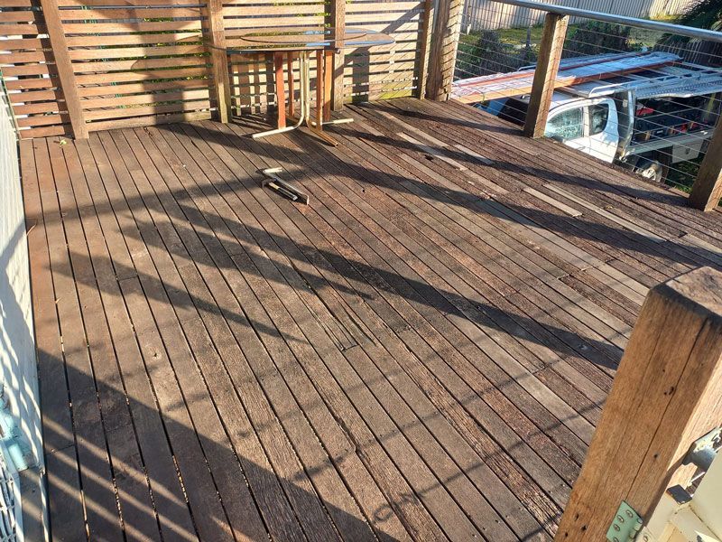 A wooden deck with a table and chairs Before — McCarthys Property Services in Glenugie, NSW