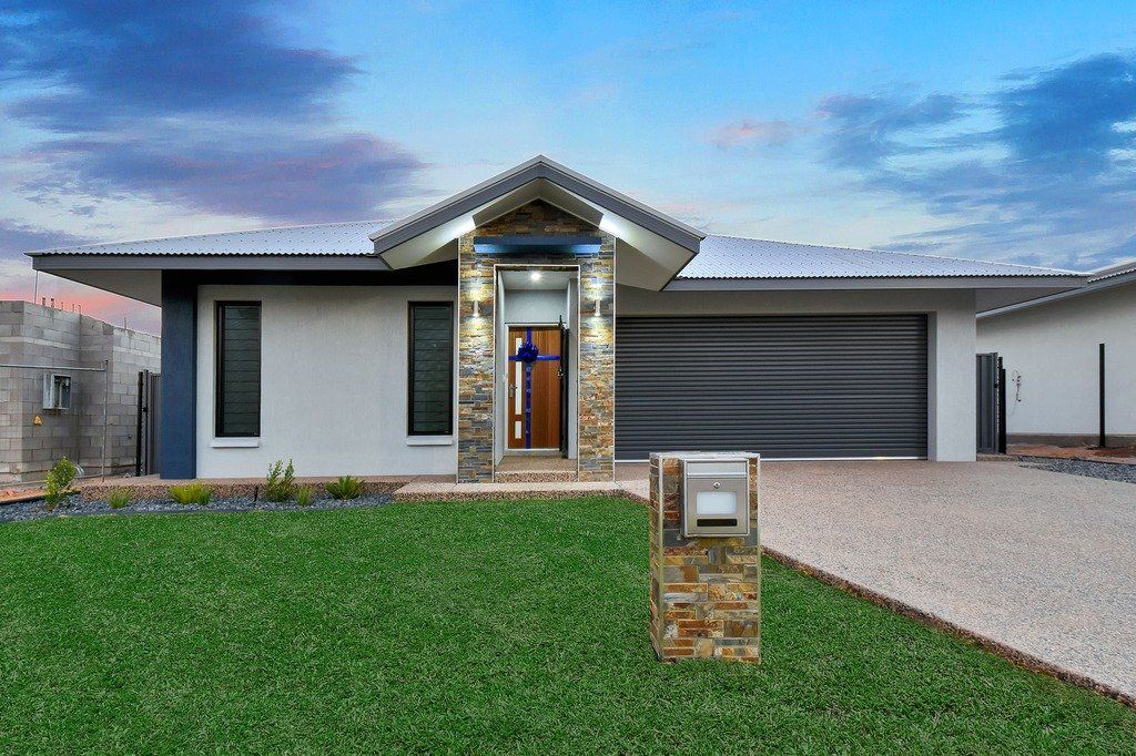A white house with a black garage door and a mailbox in front of it.