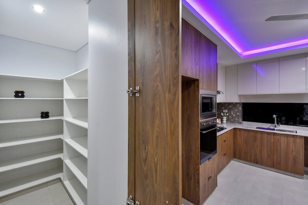 A kitchen with purple lights on the ceiling and wooden cabinets