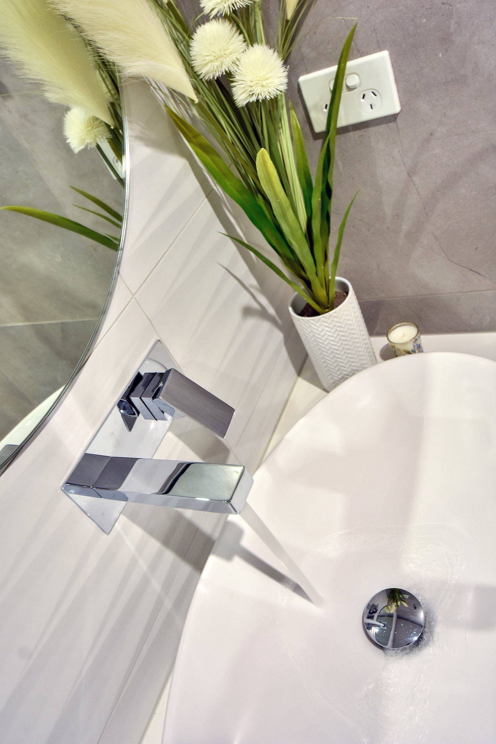 A bathroom sink with a vase of flowers next to it.