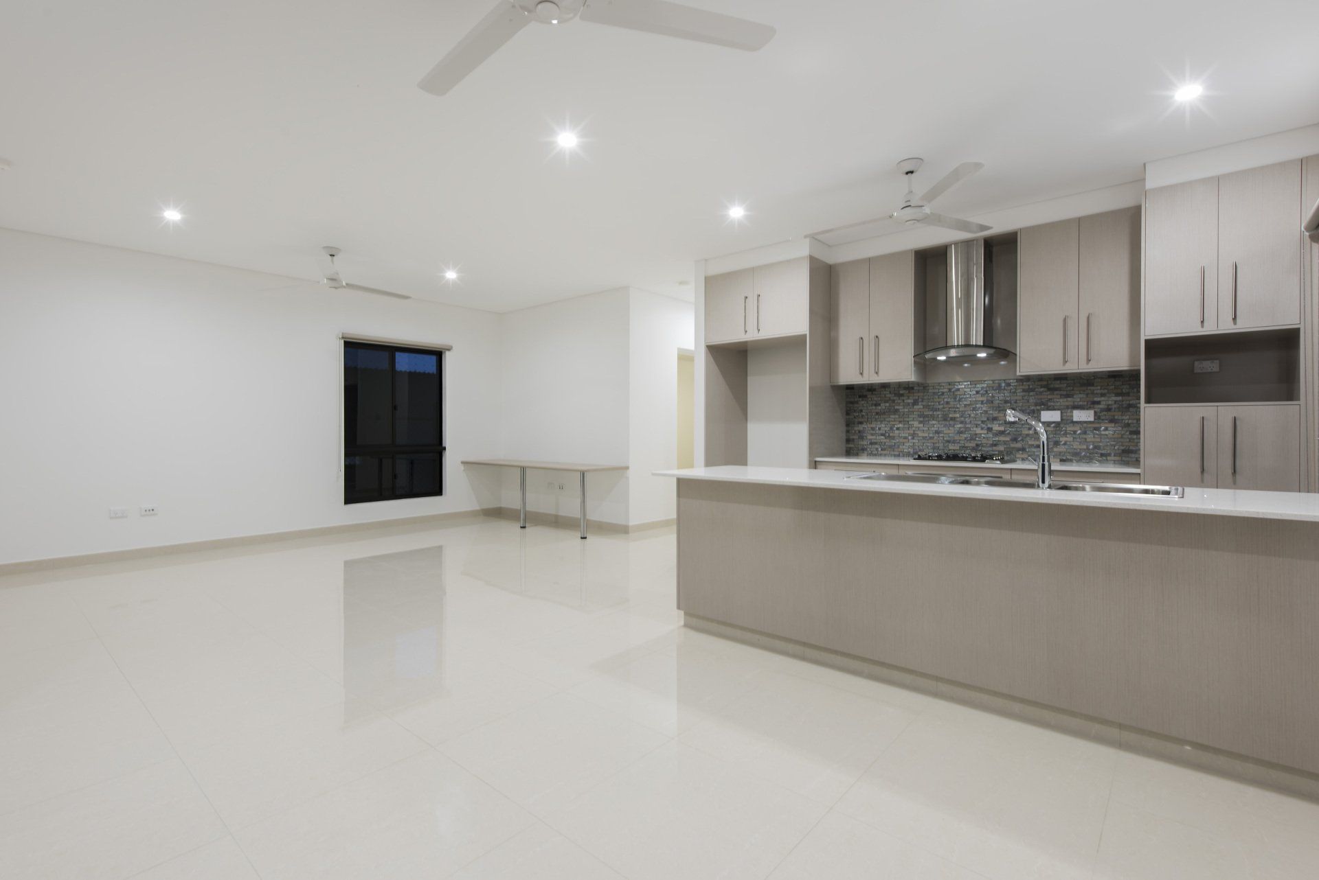An empty kitchen with white cabinets and a ceiling fan