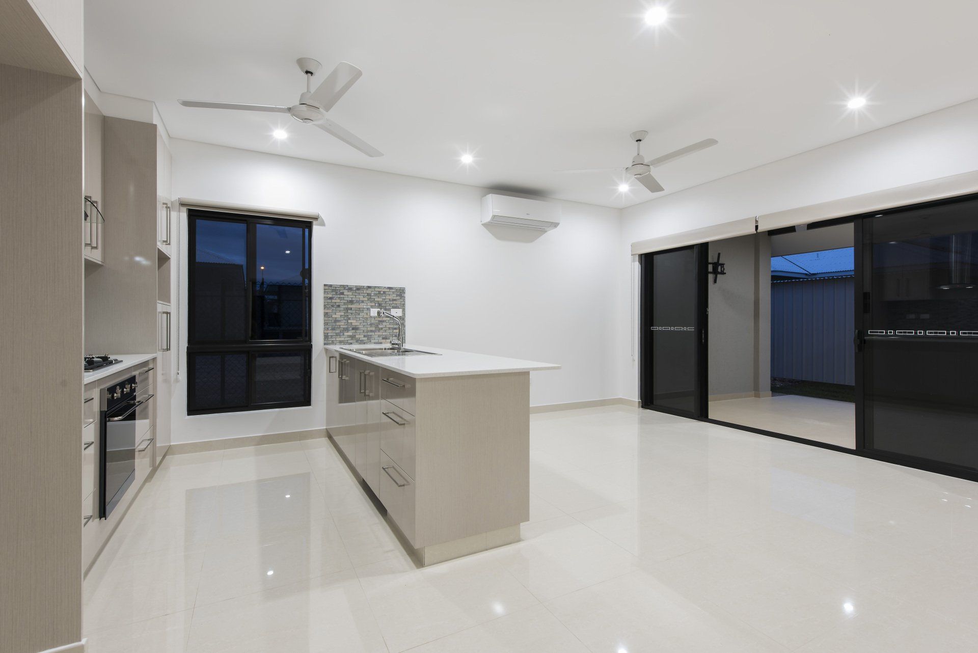 An empty kitchen with sliding glass doors and a ceiling fan.