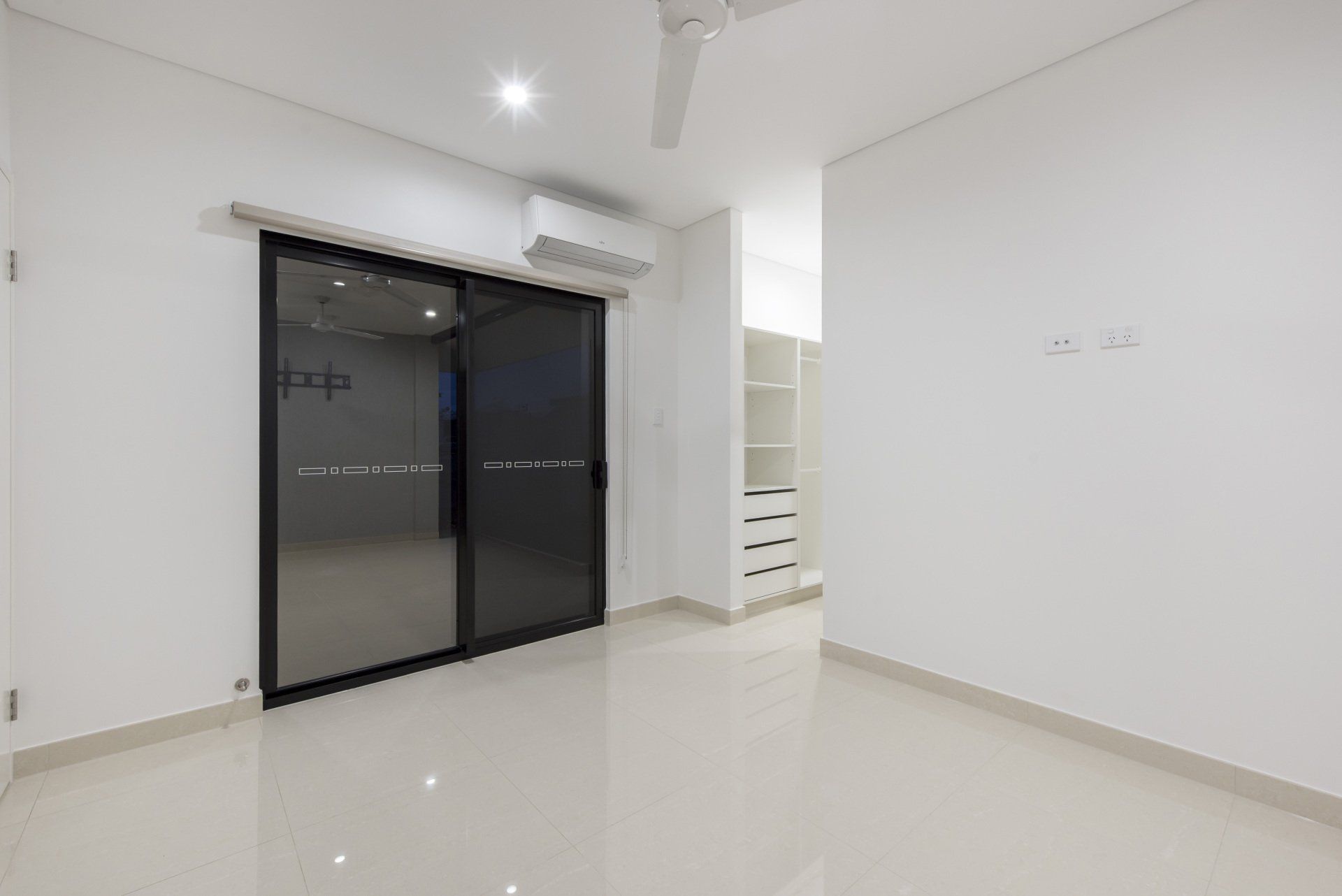 An empty room with a sliding glass door and a ceiling fan.