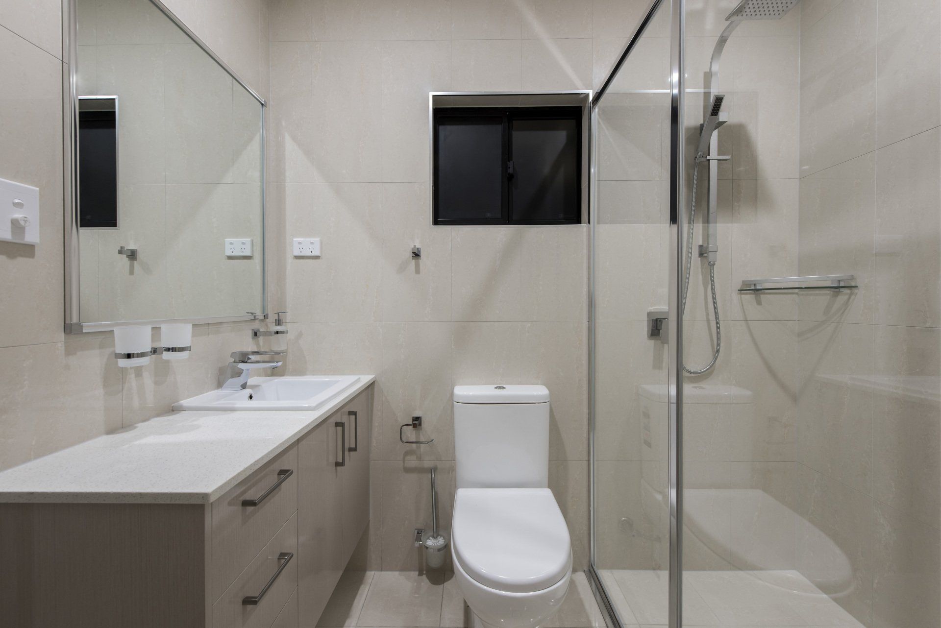 A bathroom with a toilet , sink , mirror and walk in shower.