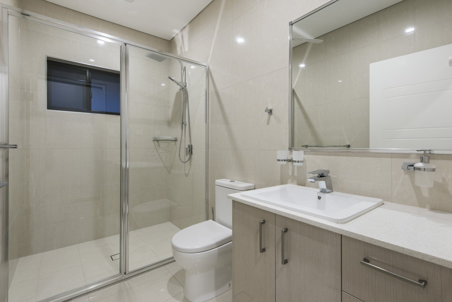 A bathroom with a toilet , sink , shower and mirror.