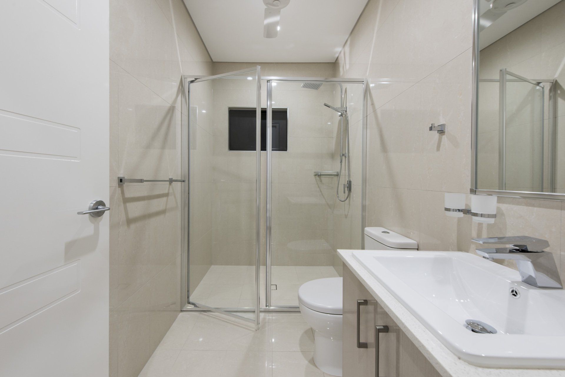 A bathroom with a toilet , sink , shower and mirror.