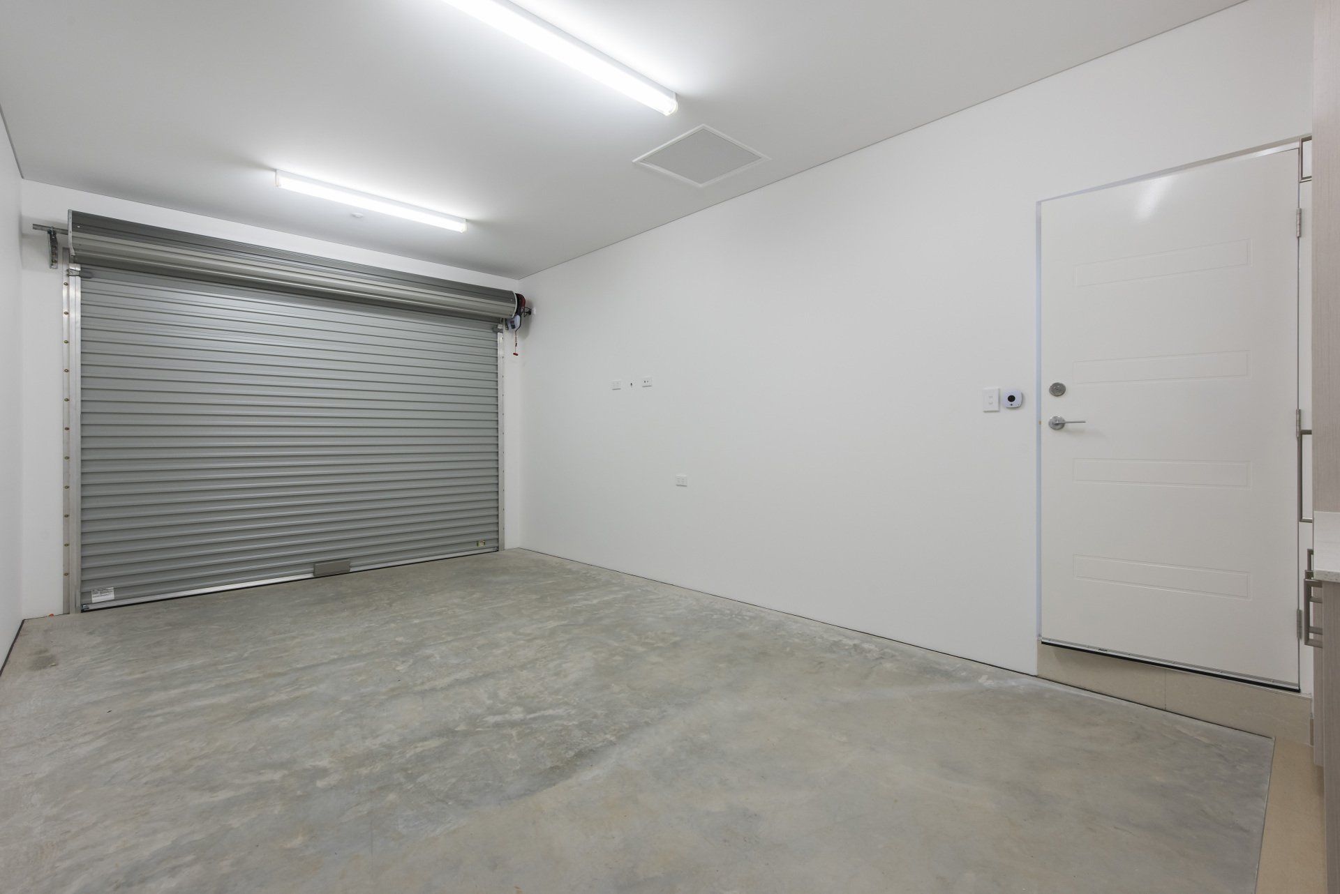 An empty room with a garage door and a doorway.