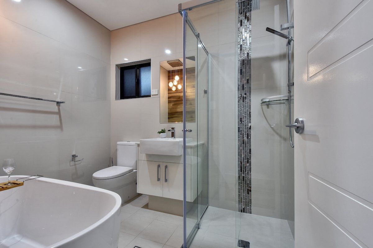 A bathroom with a tub , toilet , sink and shower.