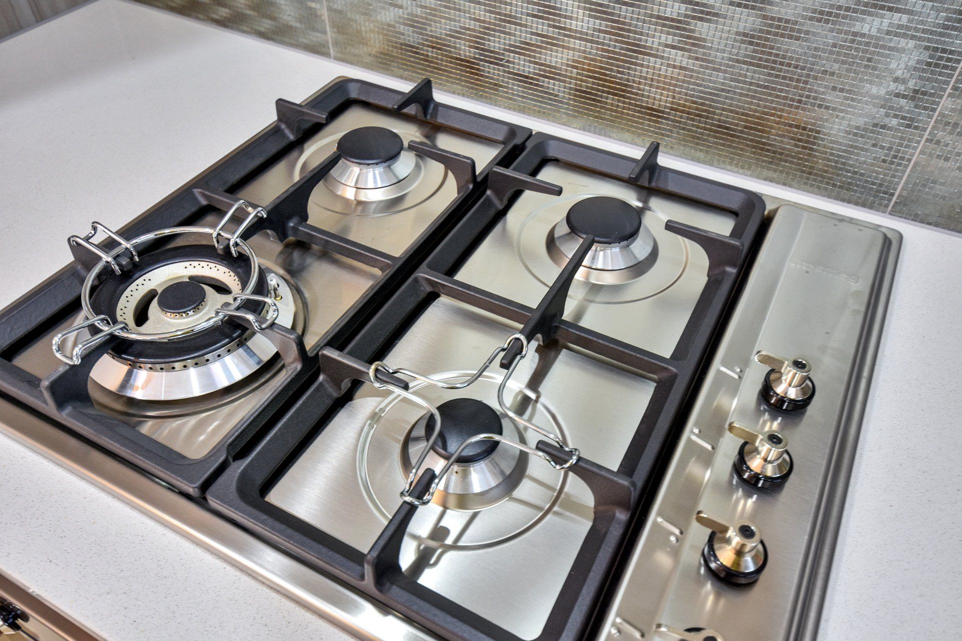 A stainless steel gas stove with four burners