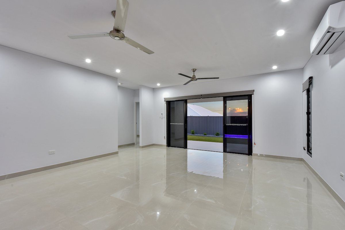 An empty living room with a ceiling fan and sliding glass doors.