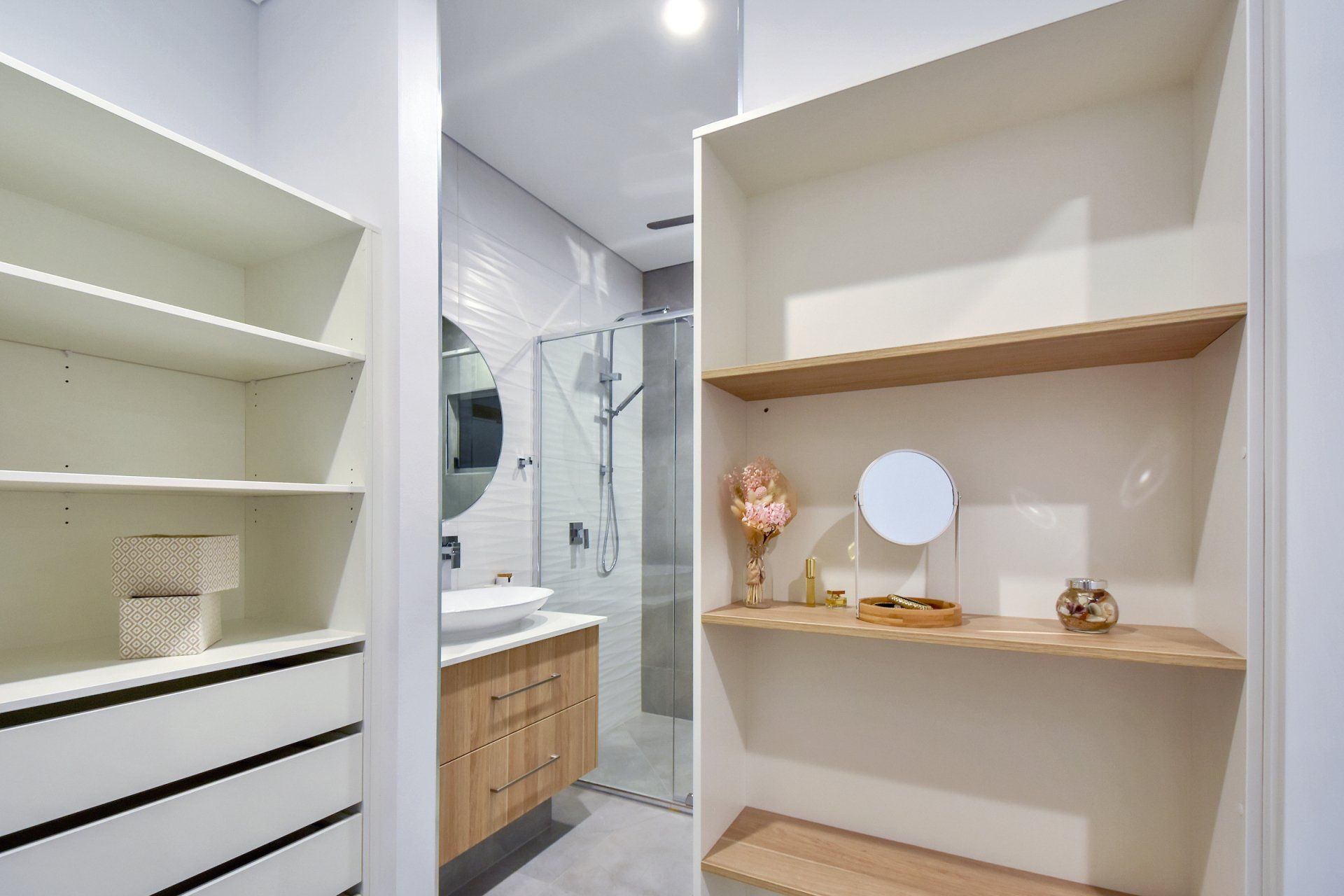 A bathroom with a sink , mirror and shelves.