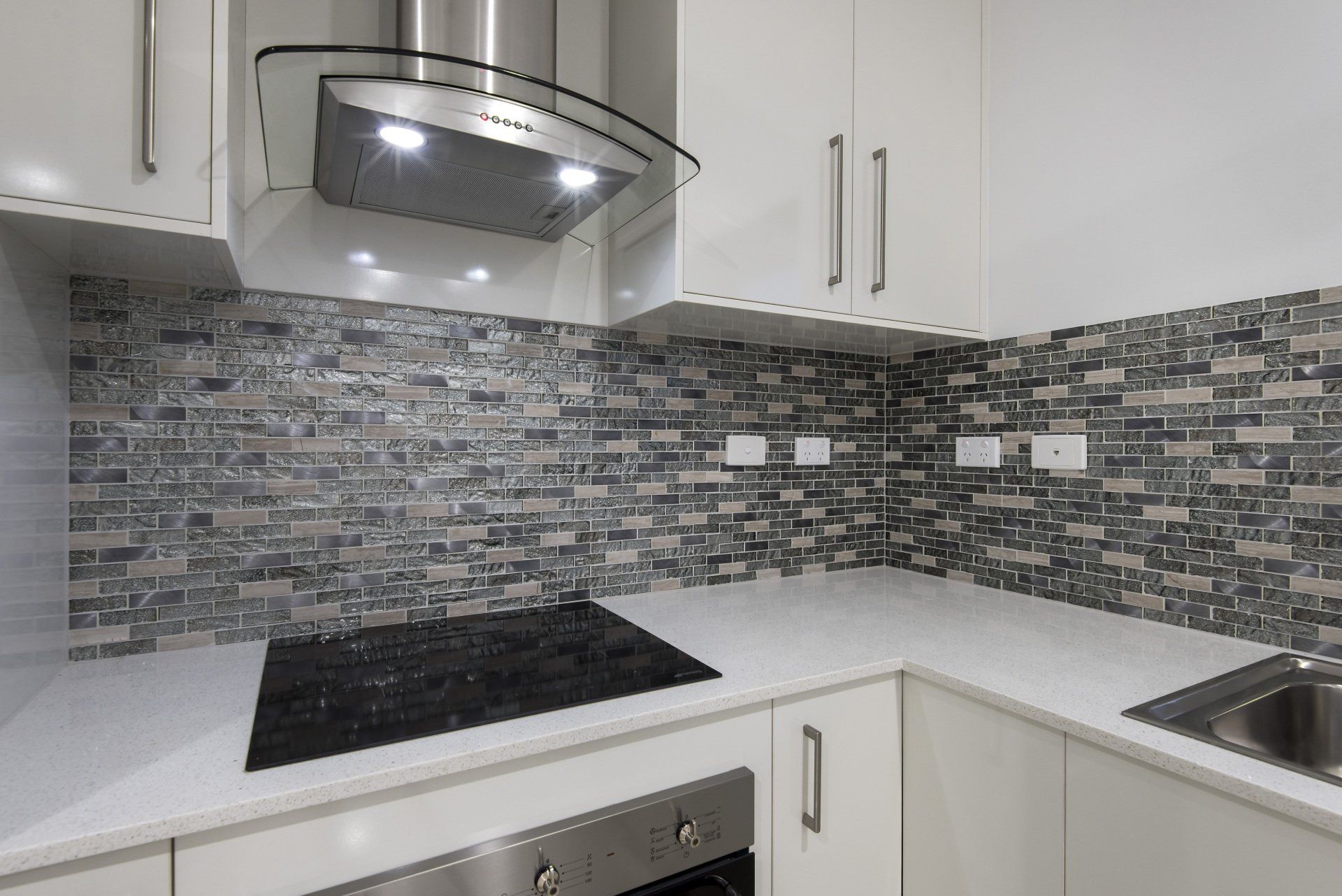A kitchen with white cabinets , stainless steel appliances and a stove top oven.
