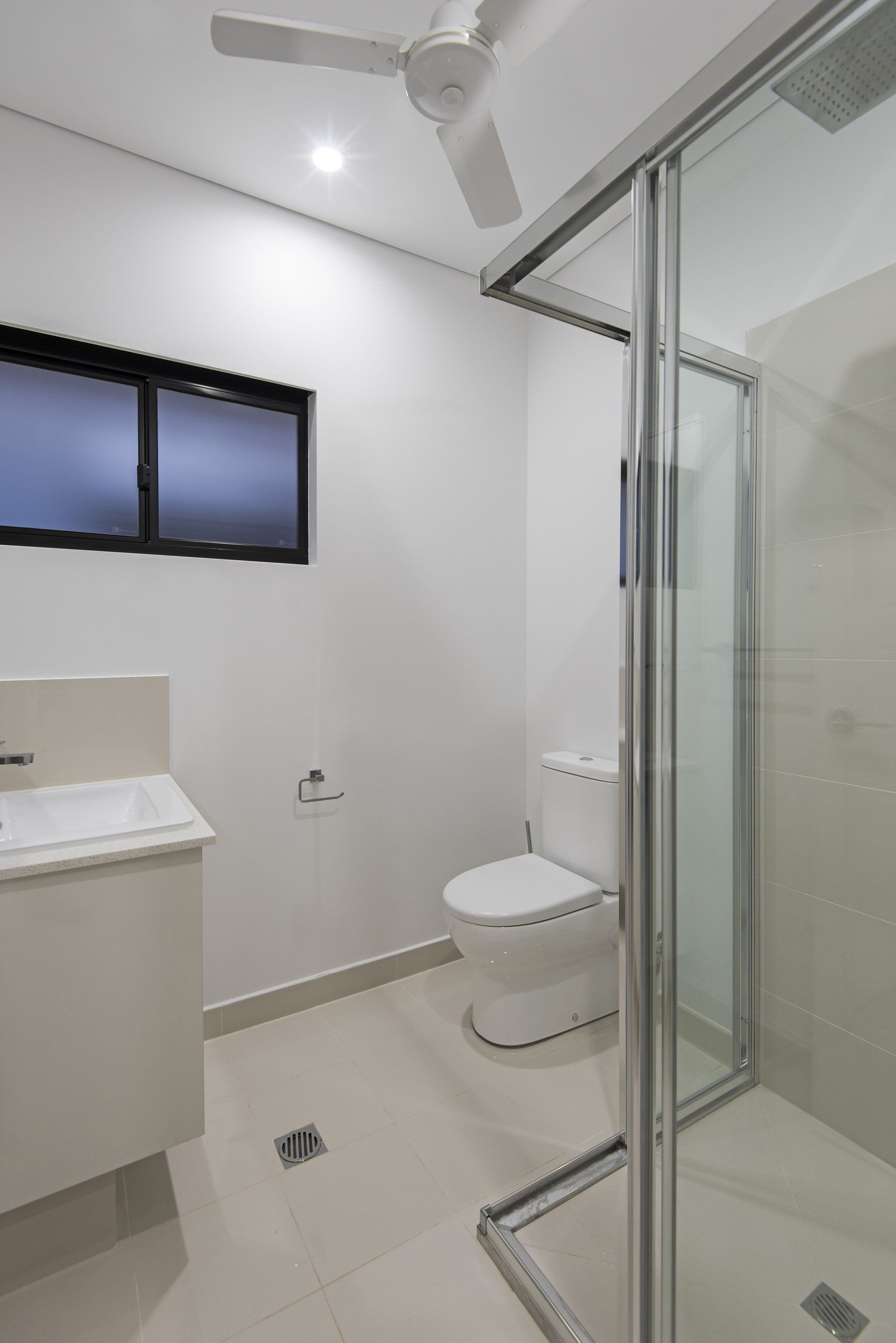 A bathroom with a toilet , sink and shower.