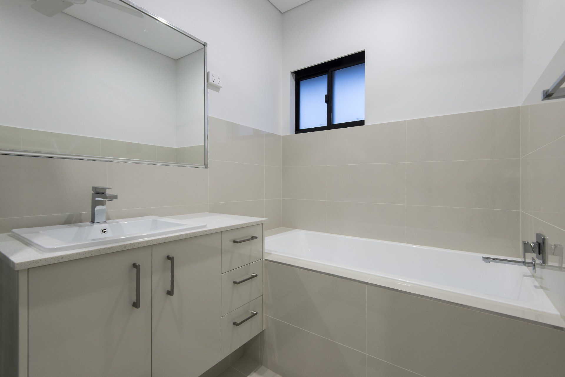 A bathroom with a tub , sink , mirror and window.