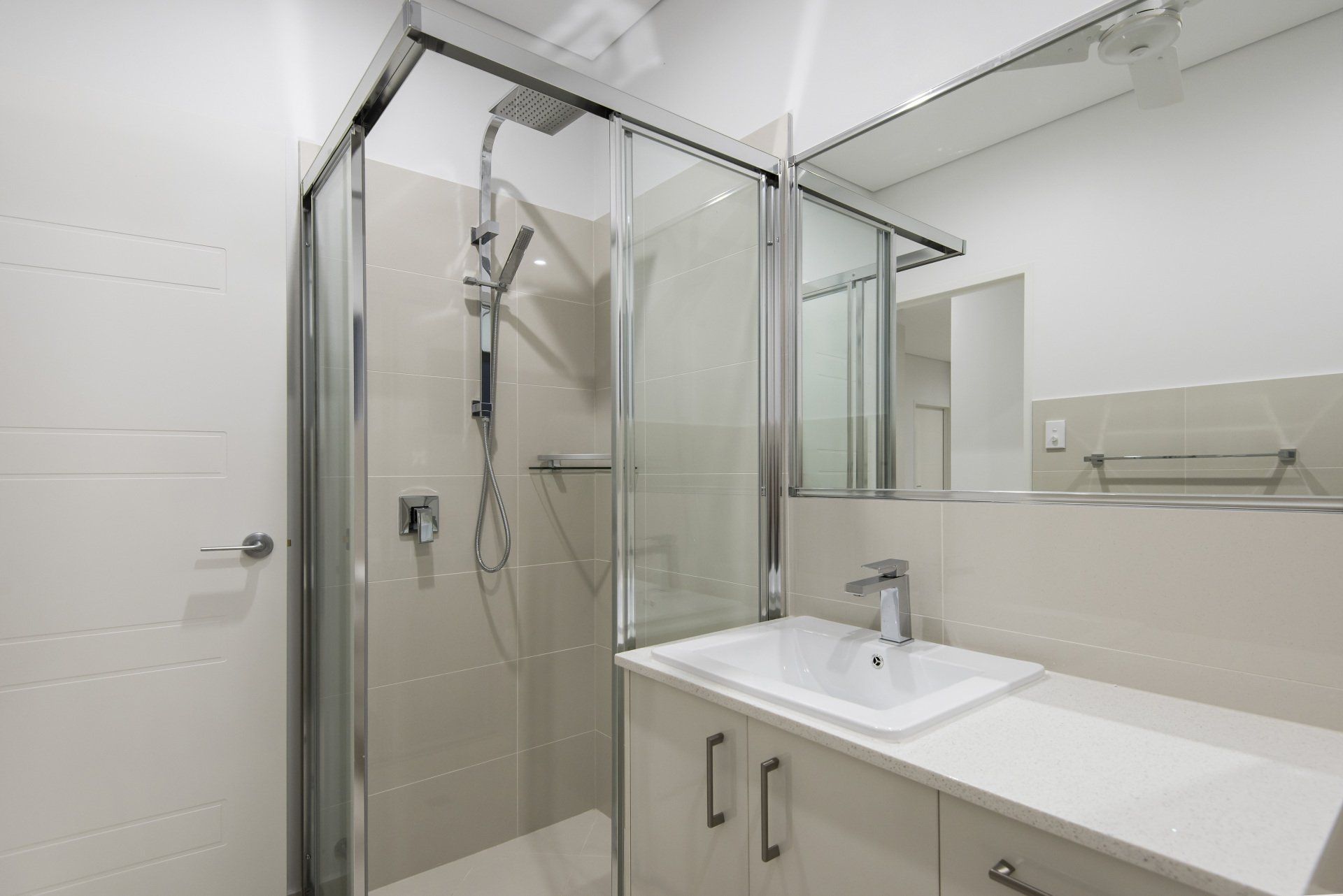 A bathroom with a sink , mirror and shower stall.