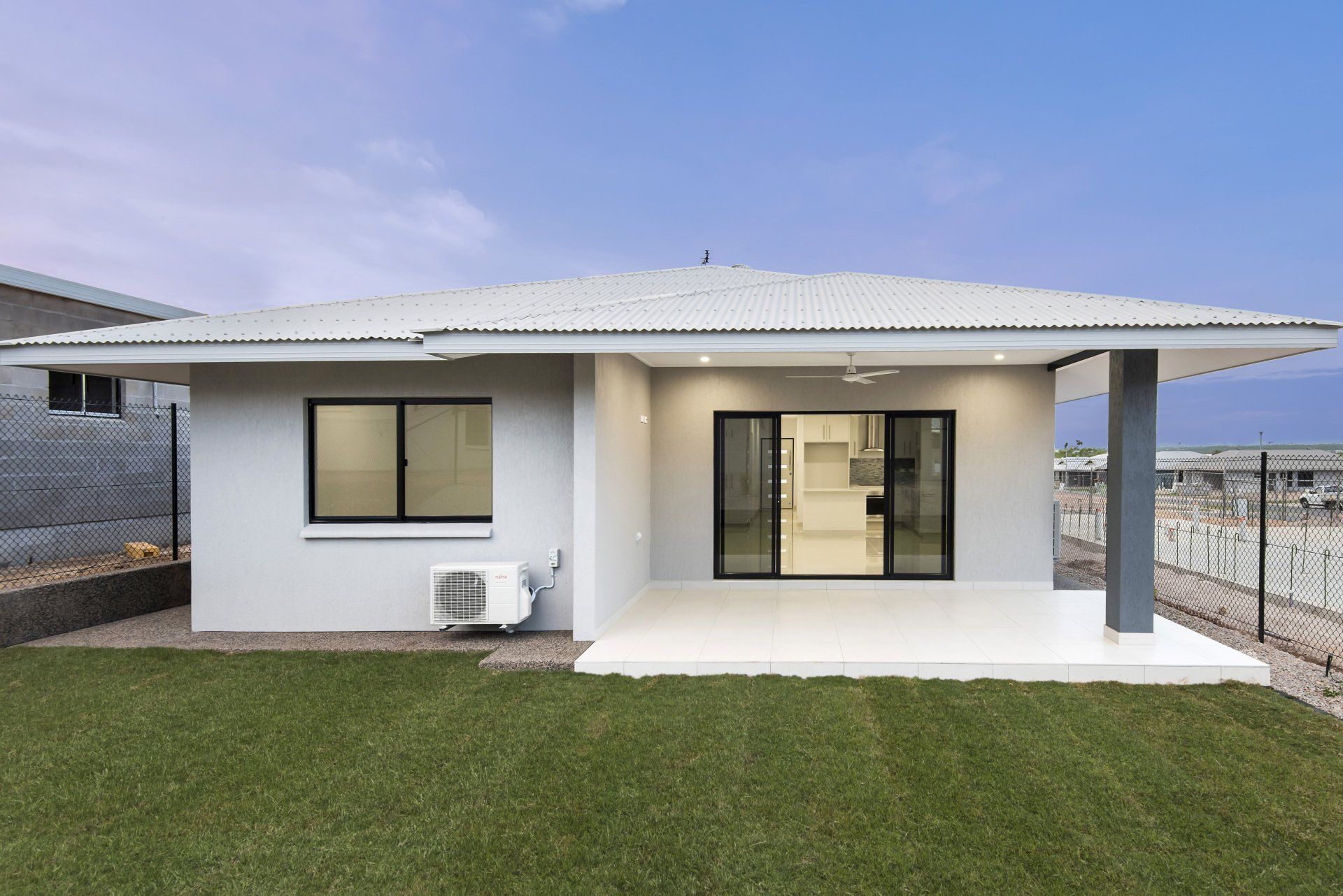 A small white house with a large lawn in front of it.