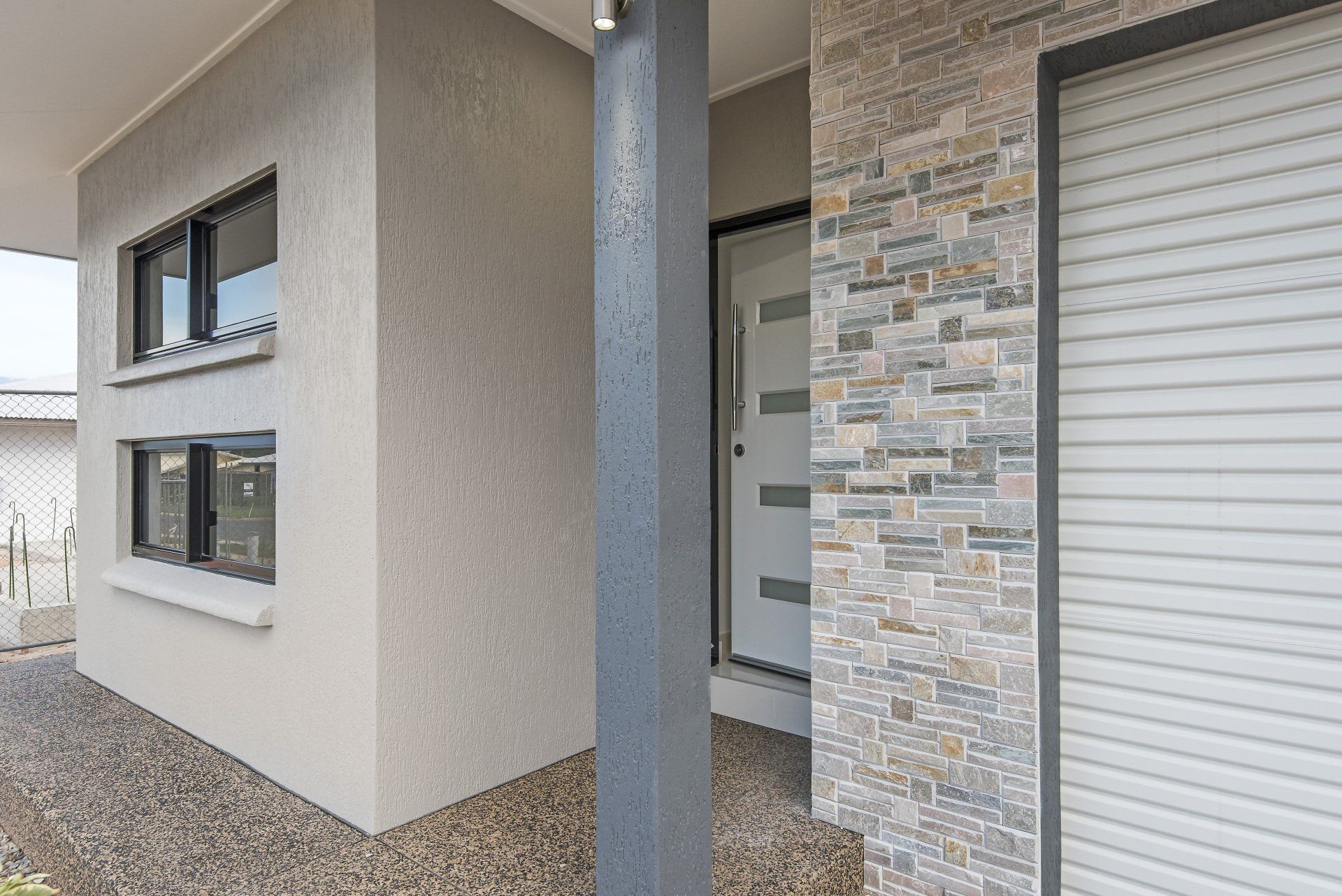 A house with a stone wall and a white garage door.