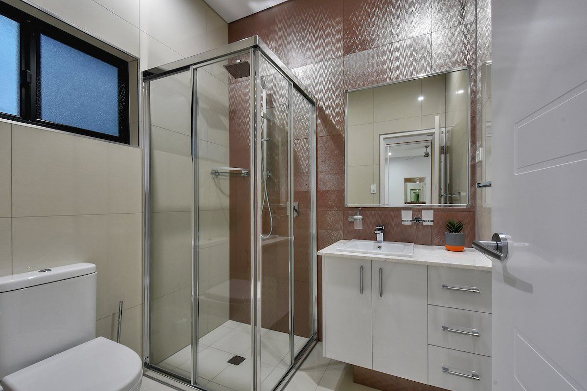 A bathroom with a toilet , sink , shower and mirror.
