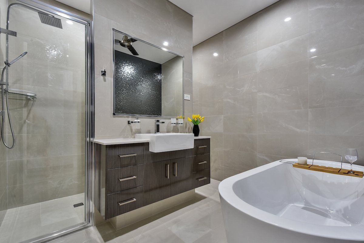 A bathroom with a tub , sink , shower and mirror.
