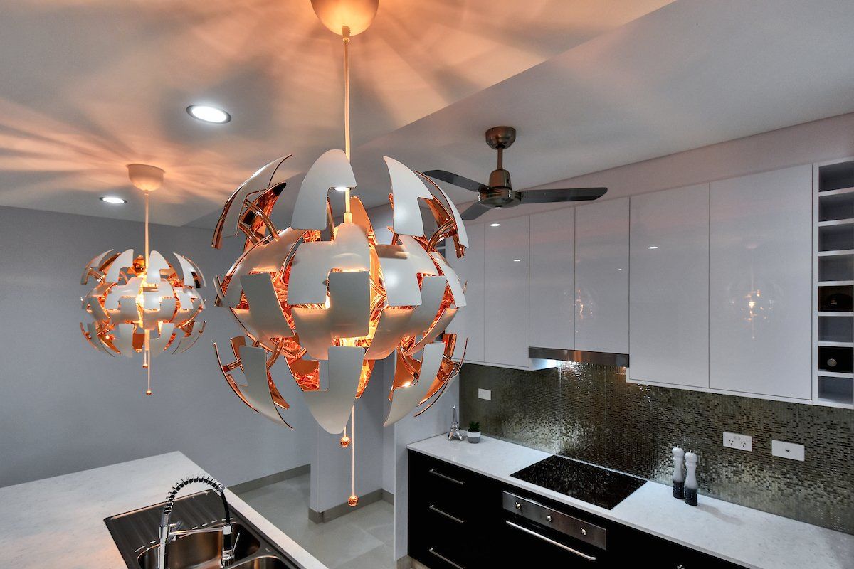 A kitchen with three chandeliers hanging from the ceiling