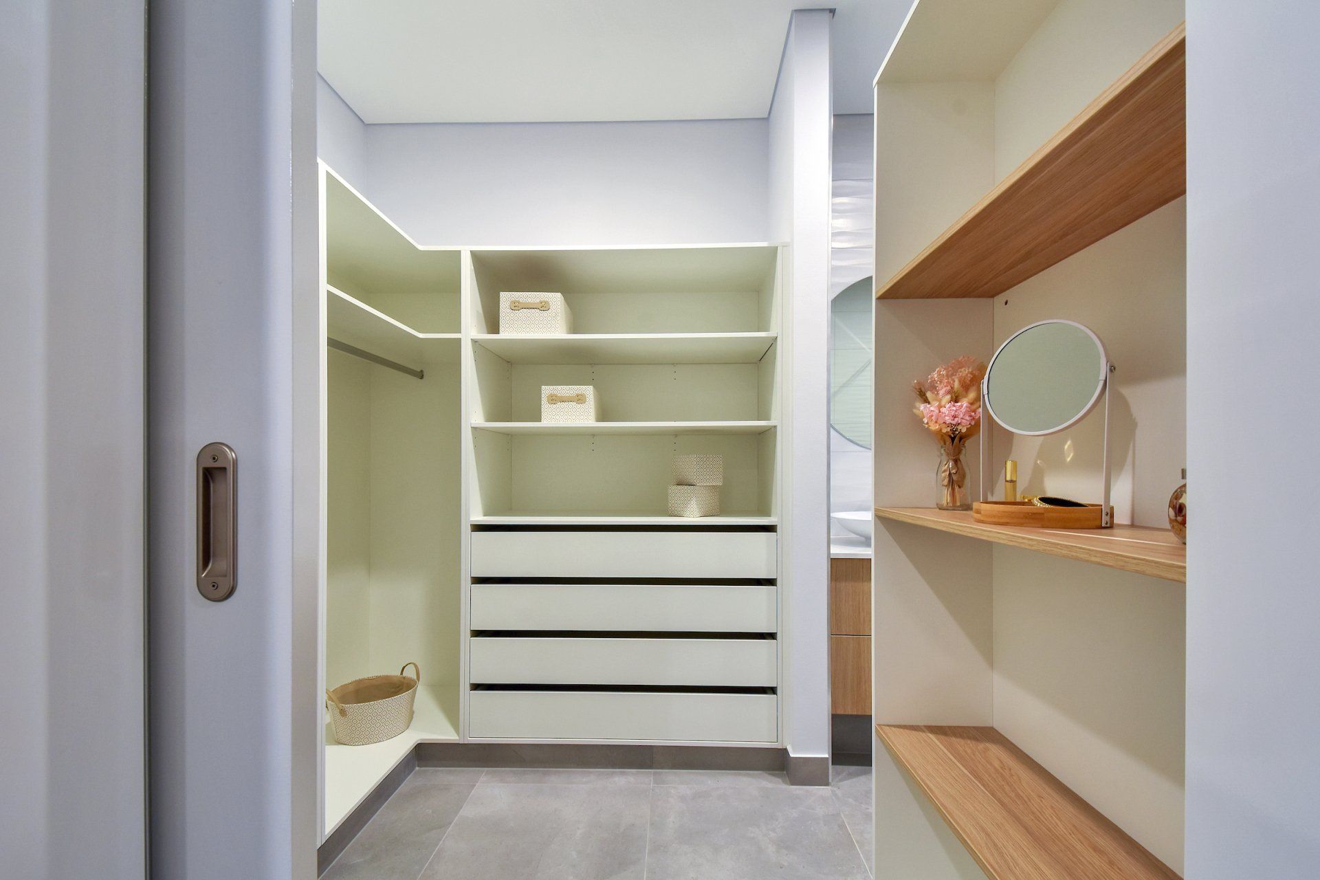 A walk in closet with lots of shelves and drawers and a mirror.