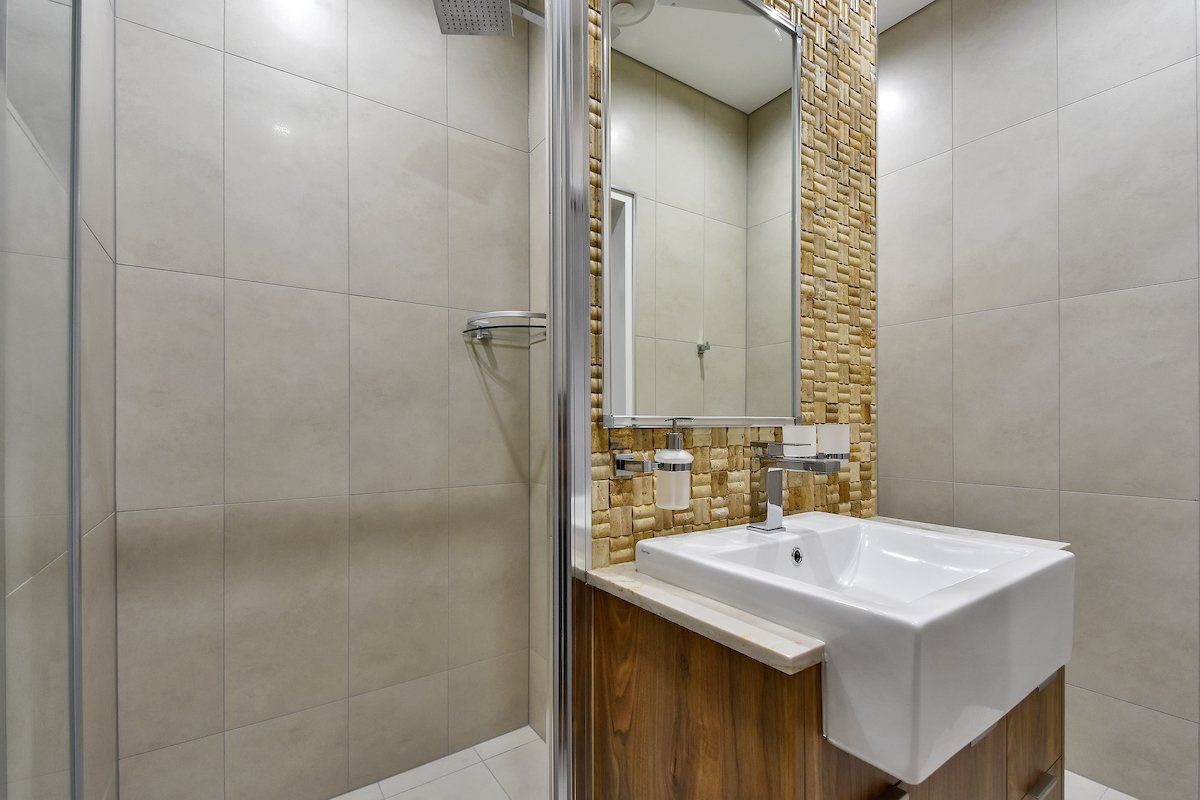 A bathroom with a sink , mirror and walk in shower.